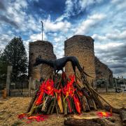 The effigy of Black Shuck, 'burning' on a pyre in front of Bungay Castle. Photo: Black Shuck Festival