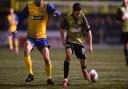 Armando Dobra of Colchester United looks to get past Jake Turner of AFC Sudbury