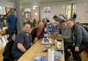 Mr Game Show joy for Kris and Ben Hall (on left of table) who visited The Repair Cafe in Bury St Edmunds and had their beloved childhood game fixed by repairers Ben and Alastair