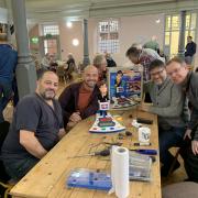 Mr Game Show joy for Kris and Ben Hall (on left of table) who visited The Repair Cafe in Bury St Edmunds and had their beloved childhood game fixed by repairers Ben and Alastair